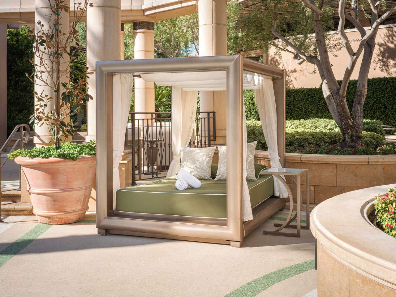 A row of daybeds in front of private poolside cabanas