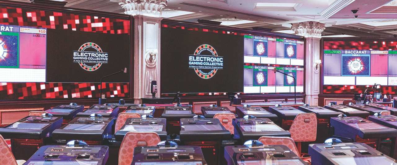 A modern gaming room with digital screens displaying "Electronic Gaming Collective" and rows of gaming stations.