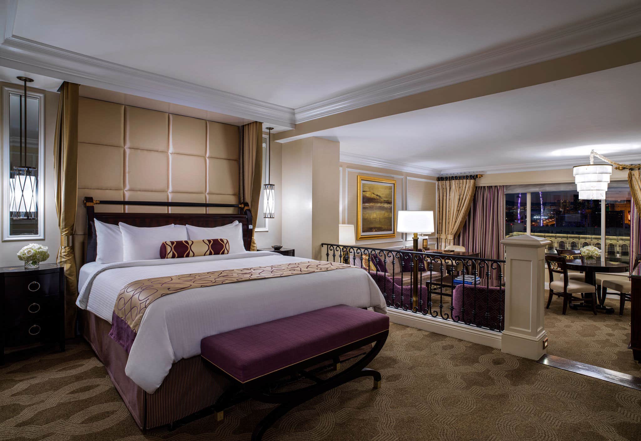 Luxurious hotel room with a king-size bed, elegant decor, a seating area, large windows, and carpeted floor.