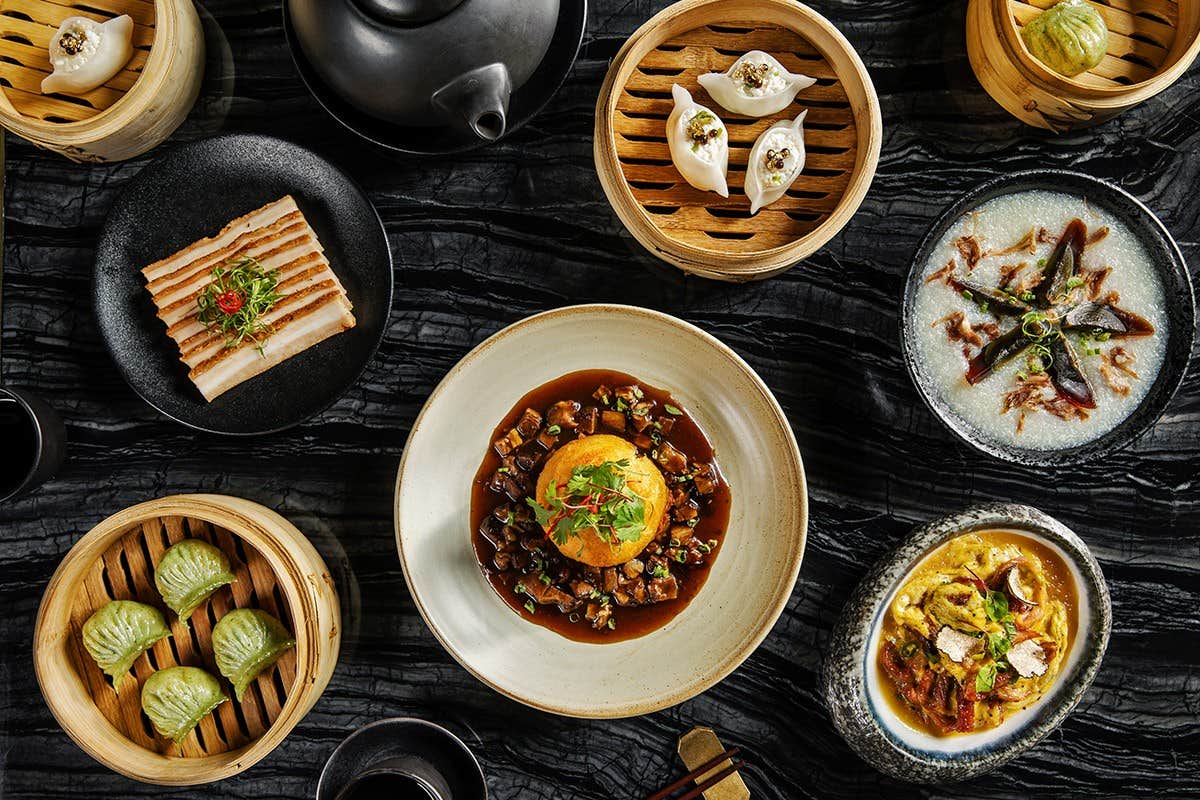 Assorted Taiwanese dishes including dumplings, a bowl of rice, and various delicacies presented on a dark textured surface.