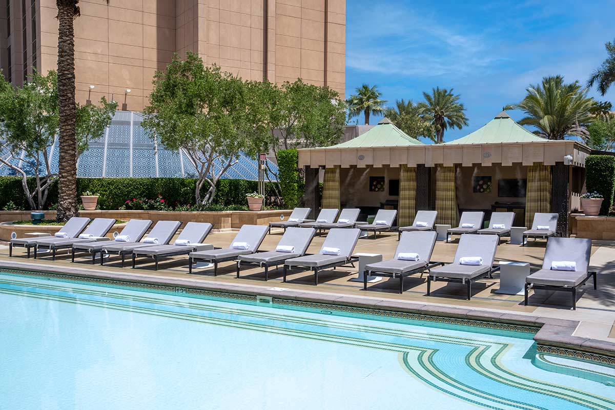 A pool with lounge chairs and a building in the background.