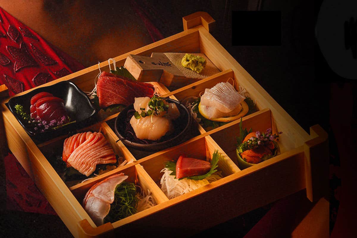 A wooden bento box with various types of sashimi and sushi in different compartments.