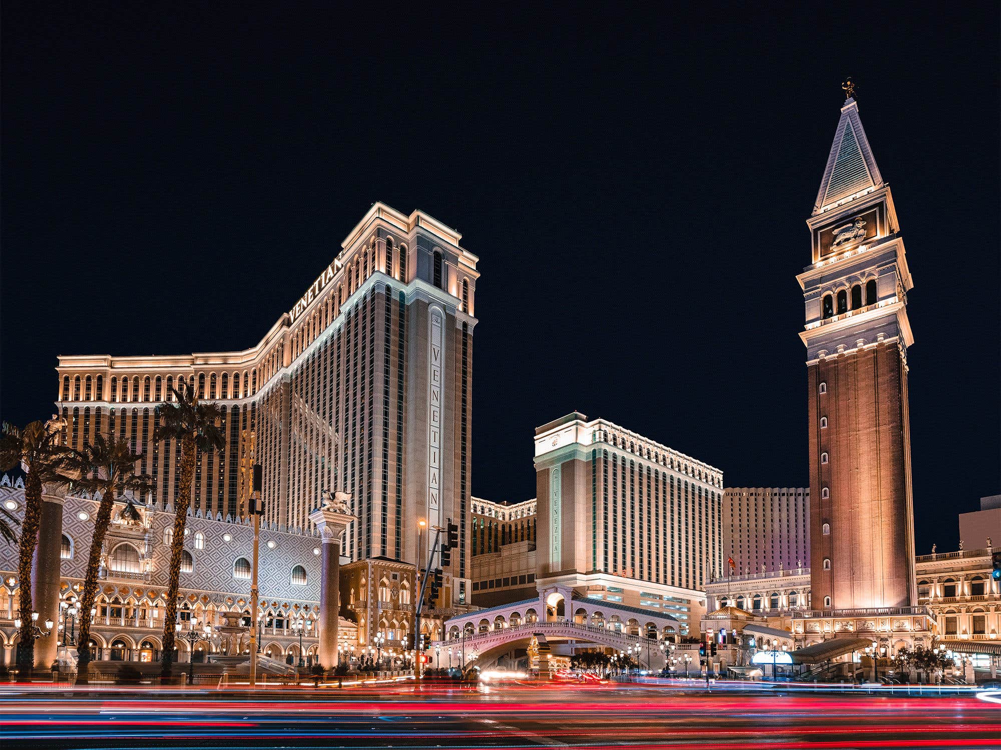 Night view of The Venetian resort in Las Vegas, showcasing its illuminated architecture and palm trees.