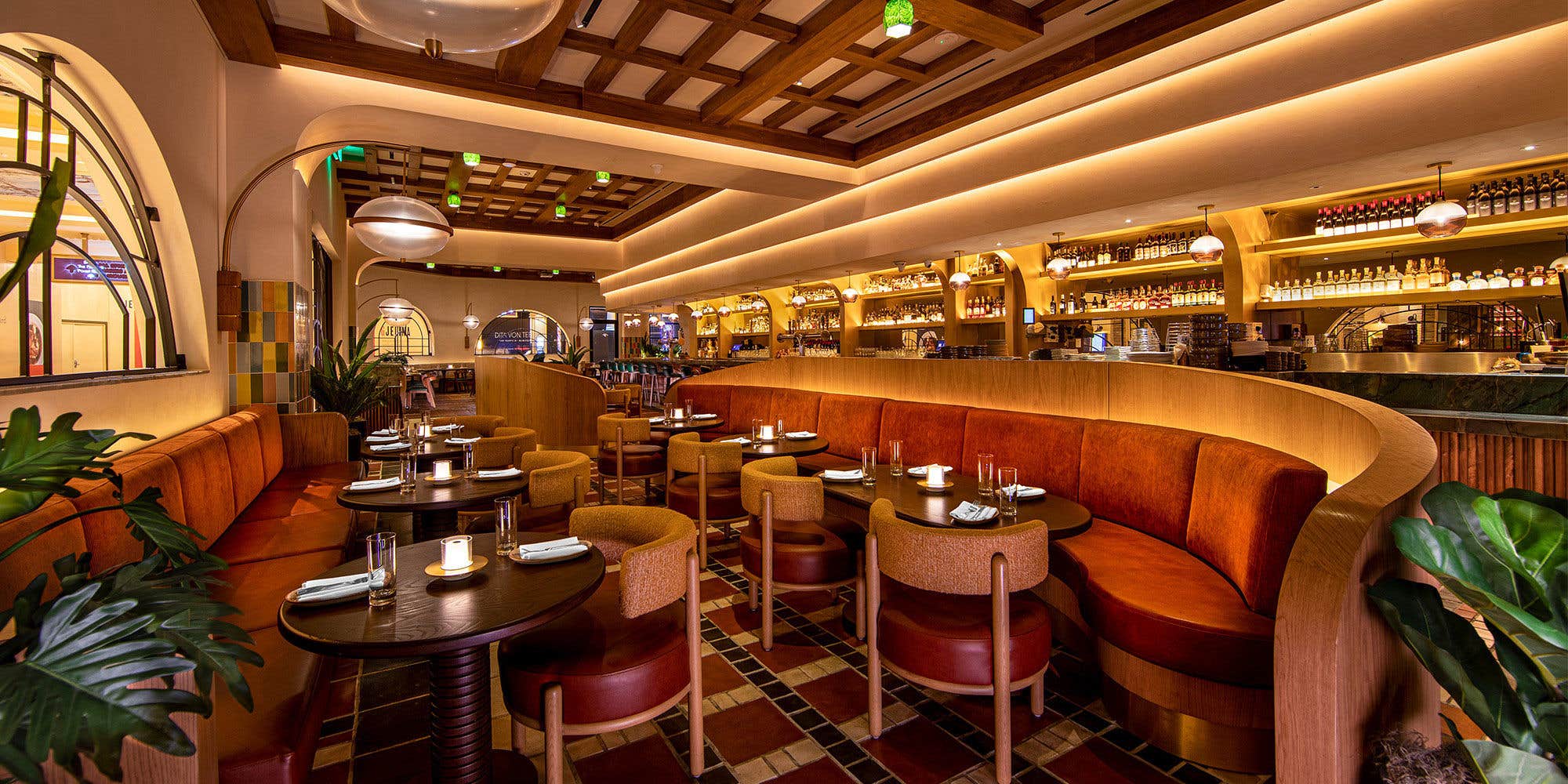 Interior of Sugarcane featuring seating with large booths, and tables and a bar in the background