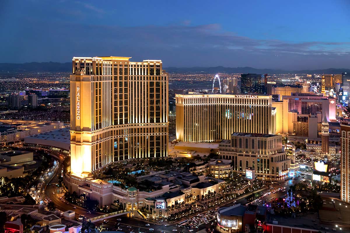 Nighttime view of illuminated Las Vegas Strip with prominent hotels and casinos against a backdrop of the city lights.