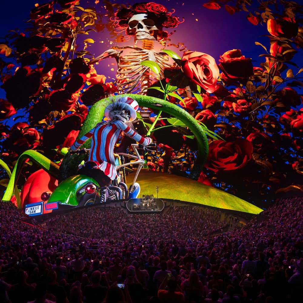 Dead and Company concert scene with a digital projection featuring a skeleton with roses and a character on a motorcycle.