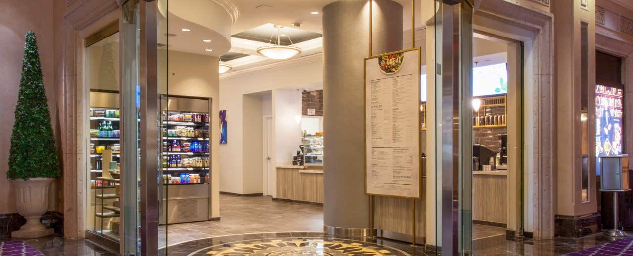 Entrance to a well-lit shop with shelves of products, a large menu, and a modern, inviting interior design.