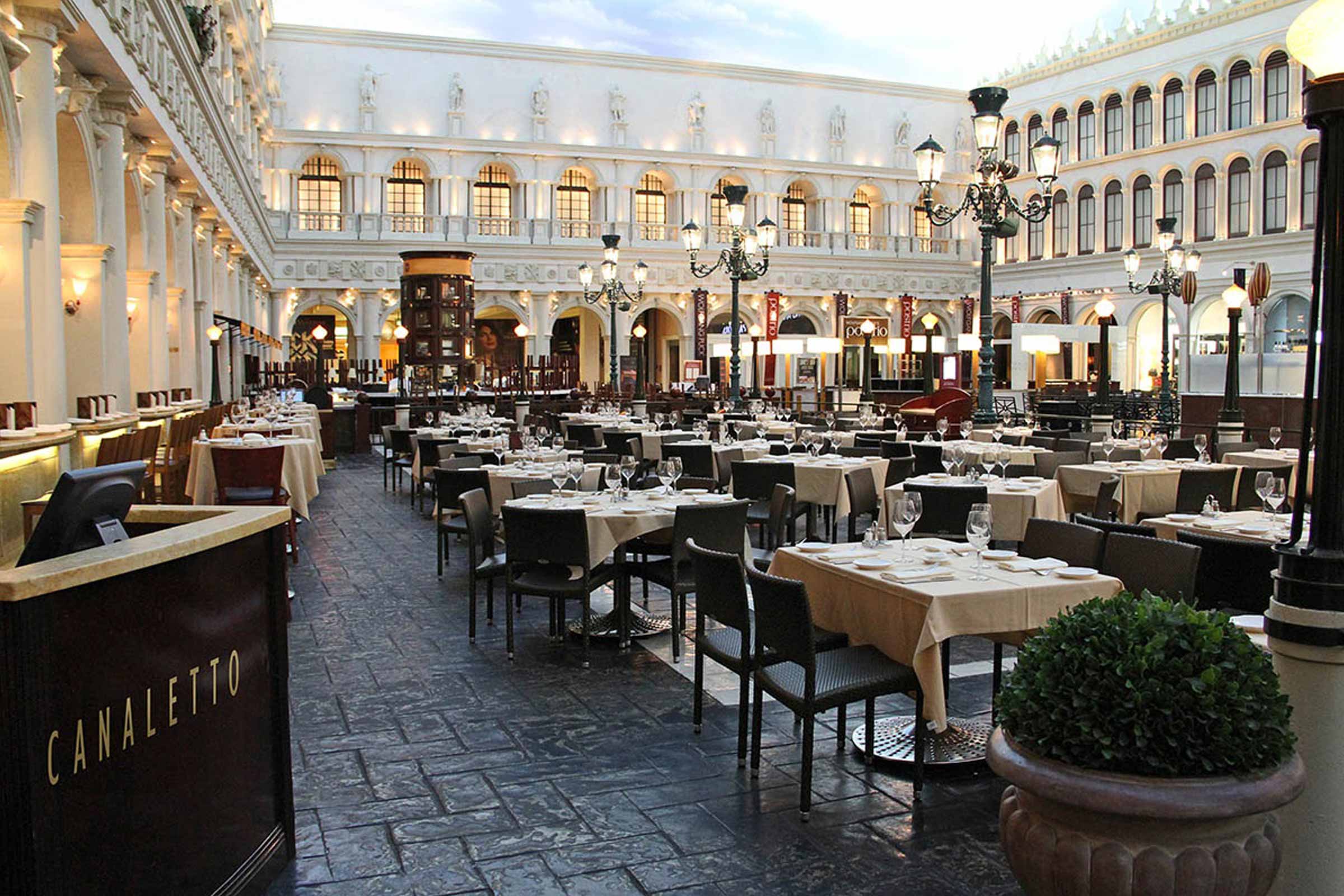 An elegant indoor restaurant with a high ceiling, ornate architecture, and tables neatly set for dining.