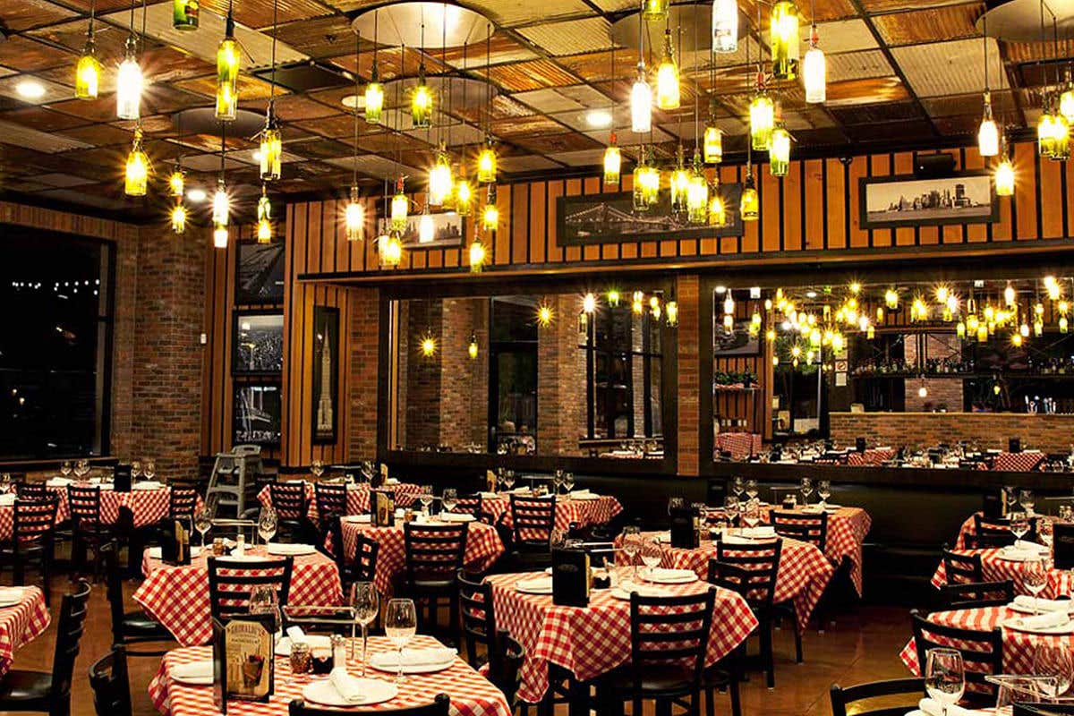 Cozy restaurant with checkered tablecloths, hanging lights, and framed pictures on the walls.