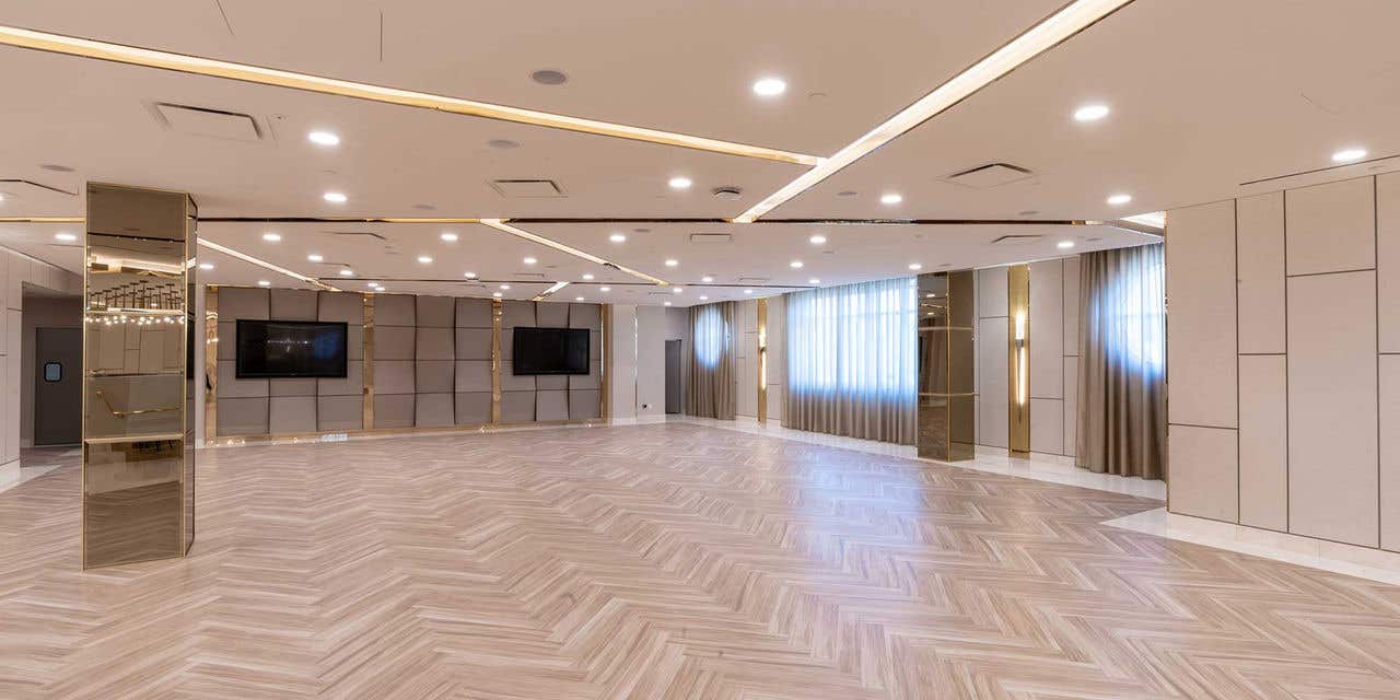 Stella Studio with a herringbone-patterned floor, ceiling lights, and wall-mounted TVs.