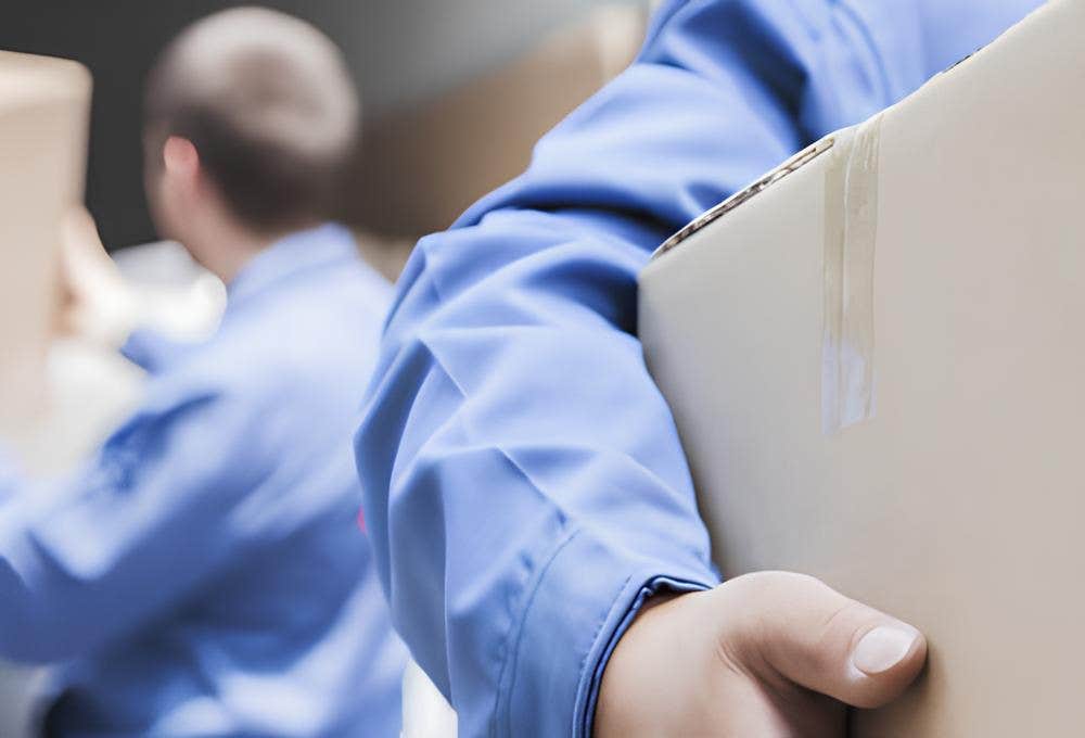 Workers in blue uniforms moving brown cardboard boxes.