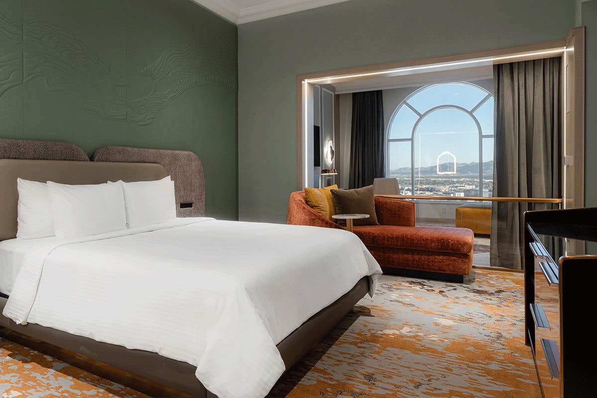 The bedroom of the Grand One Bedroom Suite with a king-sized bed, seating area, and a scenic window view.