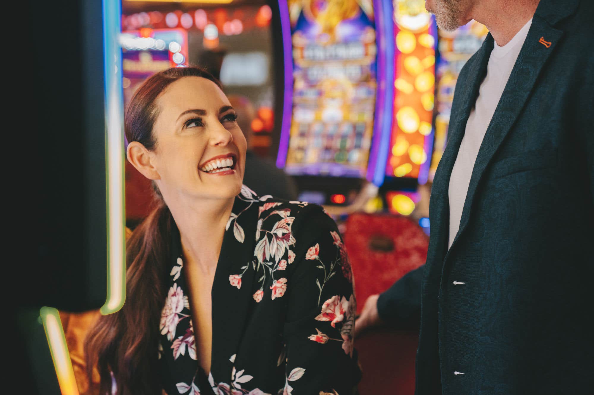 A woman at a slot machine laughing with a man