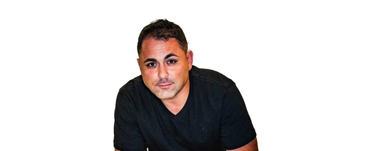 Man with short dark hair wearing a black t-shirt, posed against a white background.