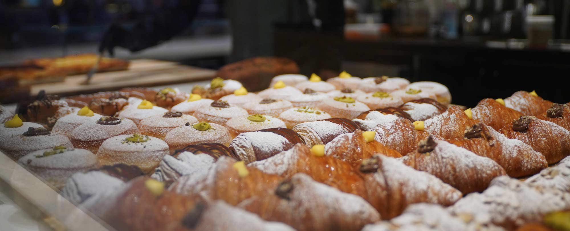 A display of assorted pastries, including croissants dusted with powdered sugar, in a bakery.