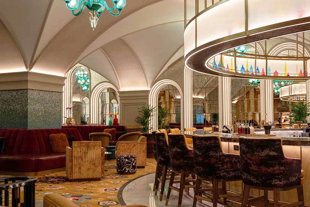 Elegant hotel bar with arched ceilings, plush seating, and ambient lighting, featuring a stylish central counter.