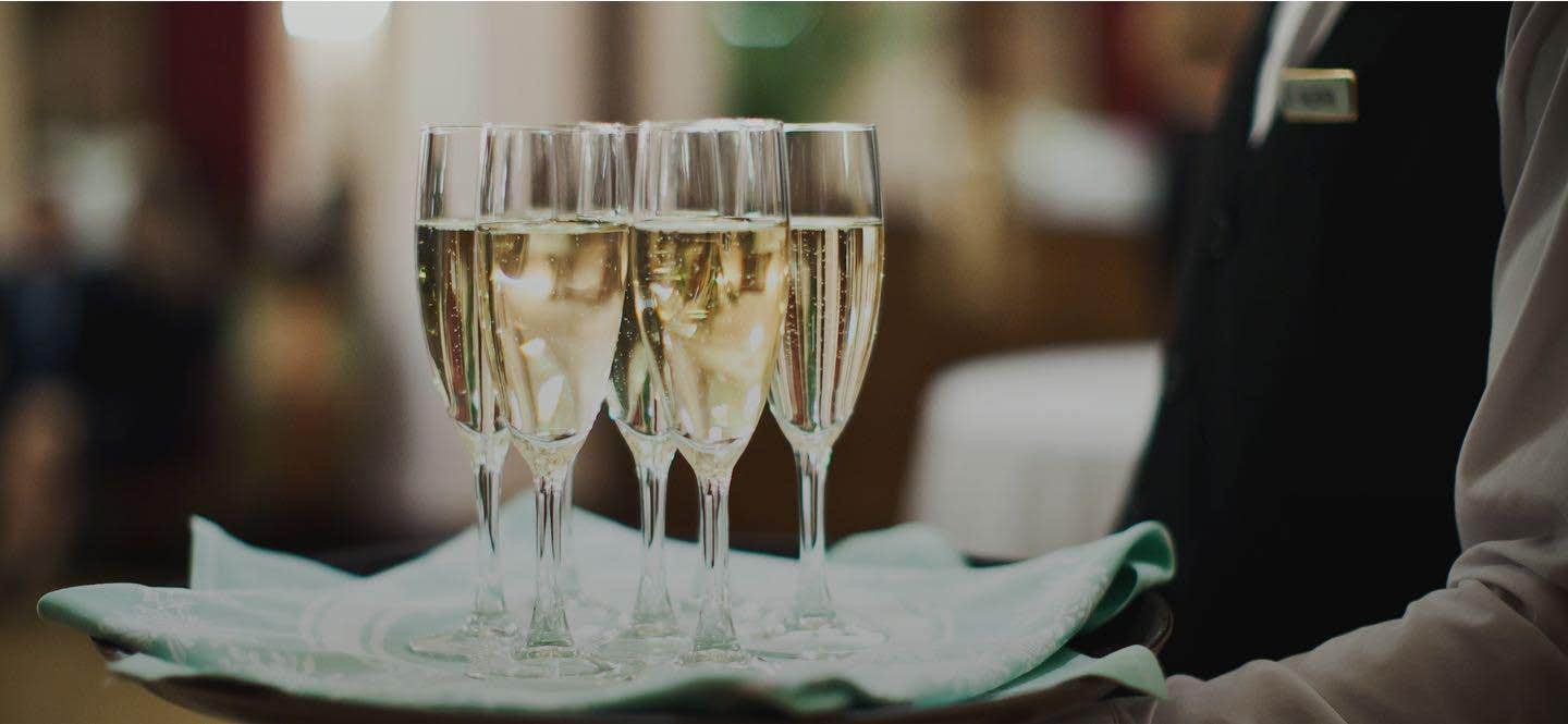 A Server with a tray of 6 glass of Champaign.