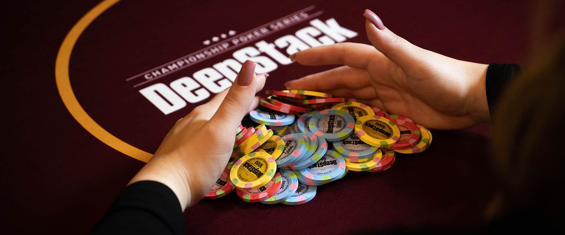 Woman's hands pulling DeepStack poker chips towards herself.