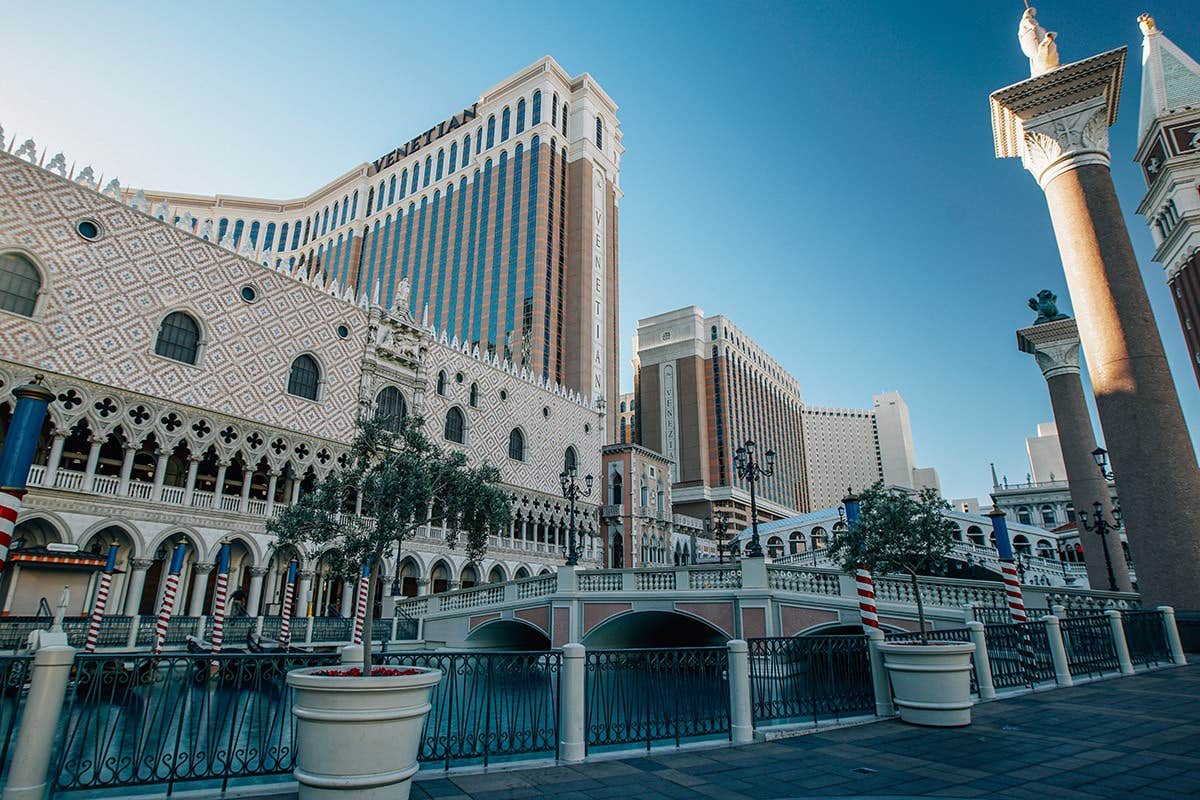 Exterior of The Venetian Resort in Las Vegas with detailed architecture and bridges over a waterway against a clear blue sky.