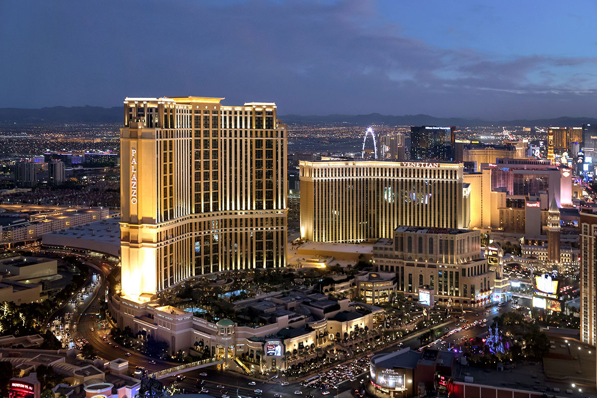 Aerial view of Las Vegas Strip at dusk, featuring illuminated hotels, casinos, and the High Roller Ferris wheel.