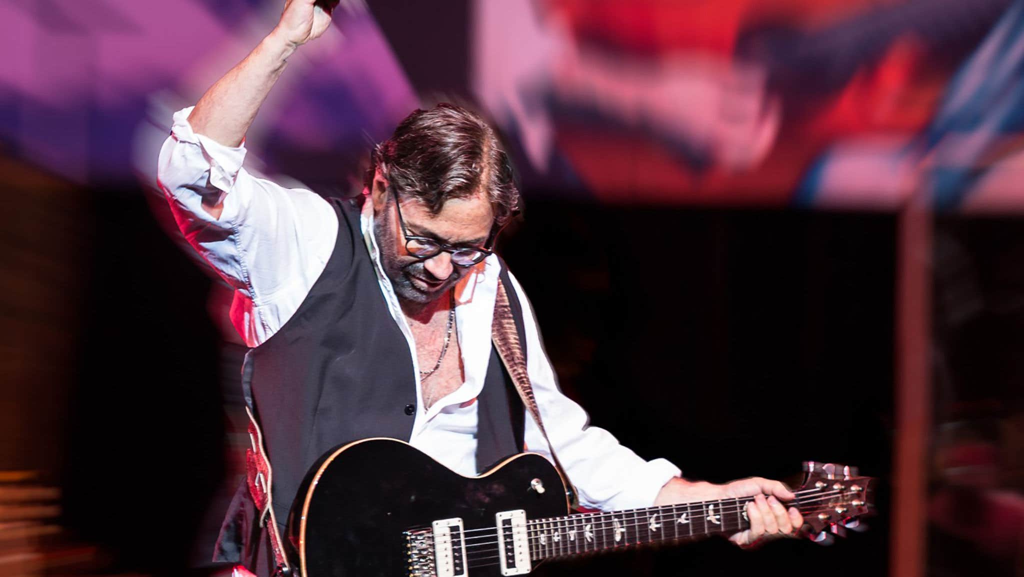 Al Di Meola strumming his guitar.