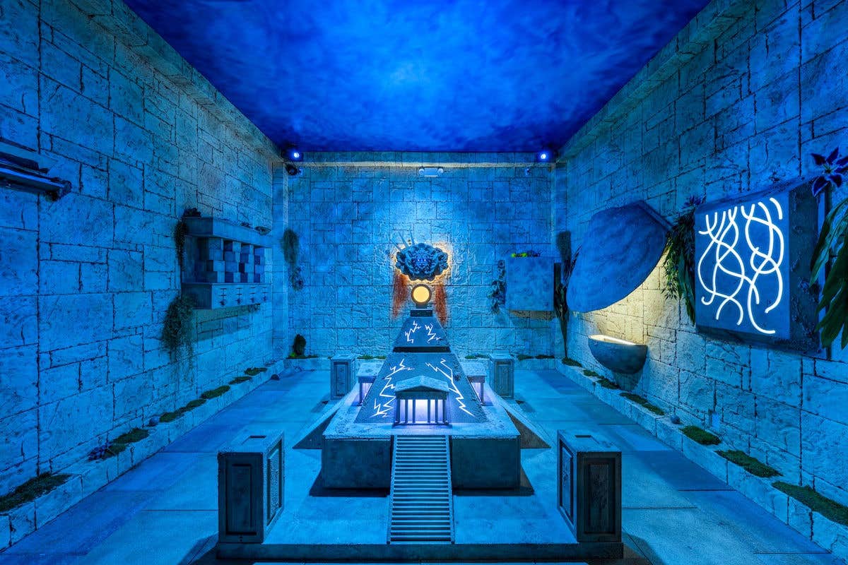 Blue room with stone walls and floor with old artifacts hung on the walls.