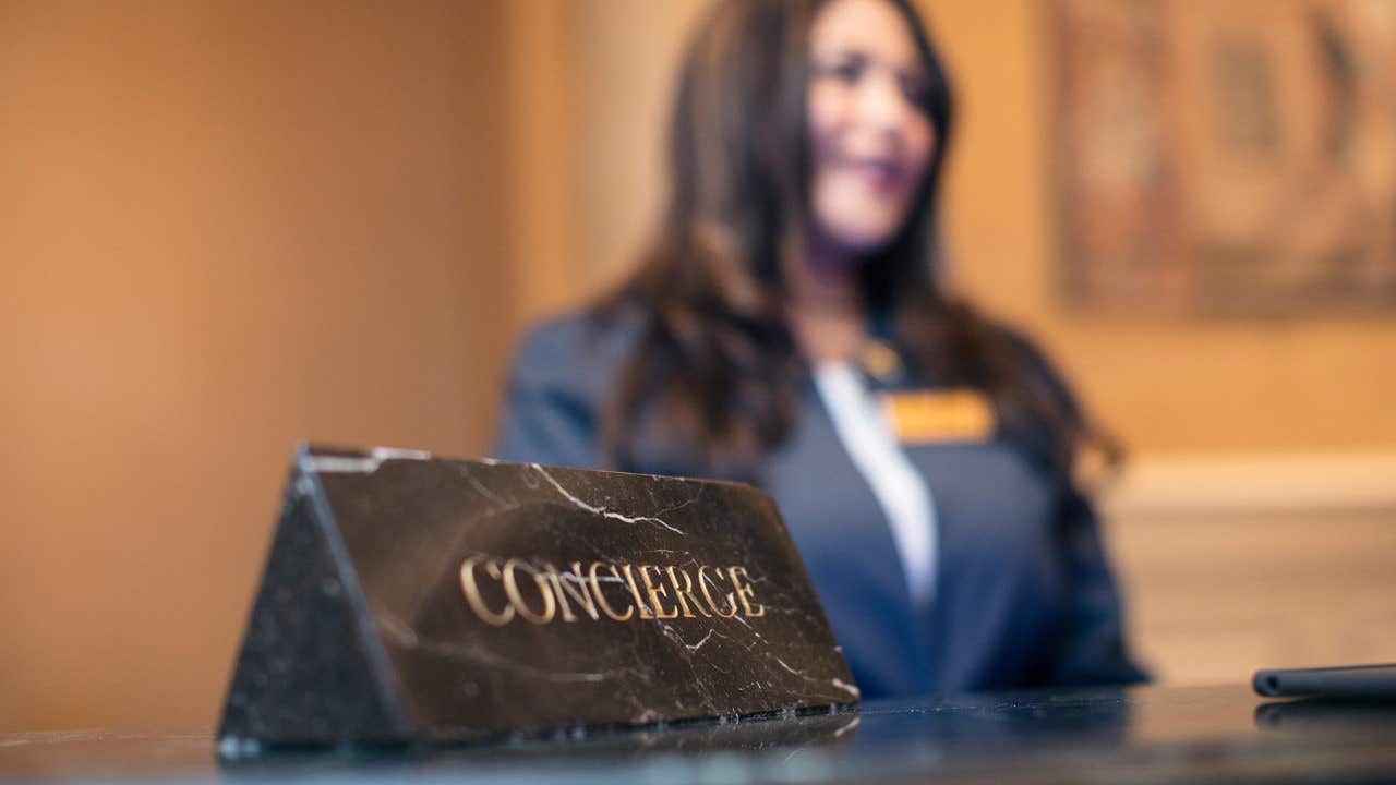 Concierge sign on a counter in a las vegas hotel with an out-of-focus woman in a suit standing in the background.