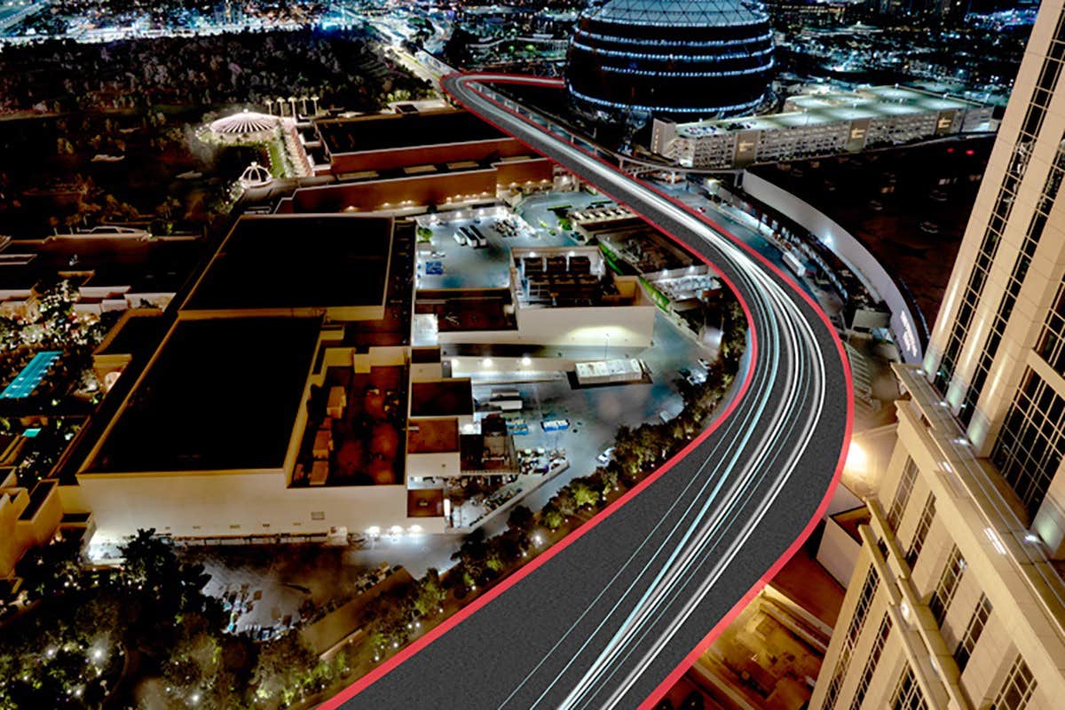 Aerial nighttime view of a cityscape with streaks of light from vehicles on a curved road.