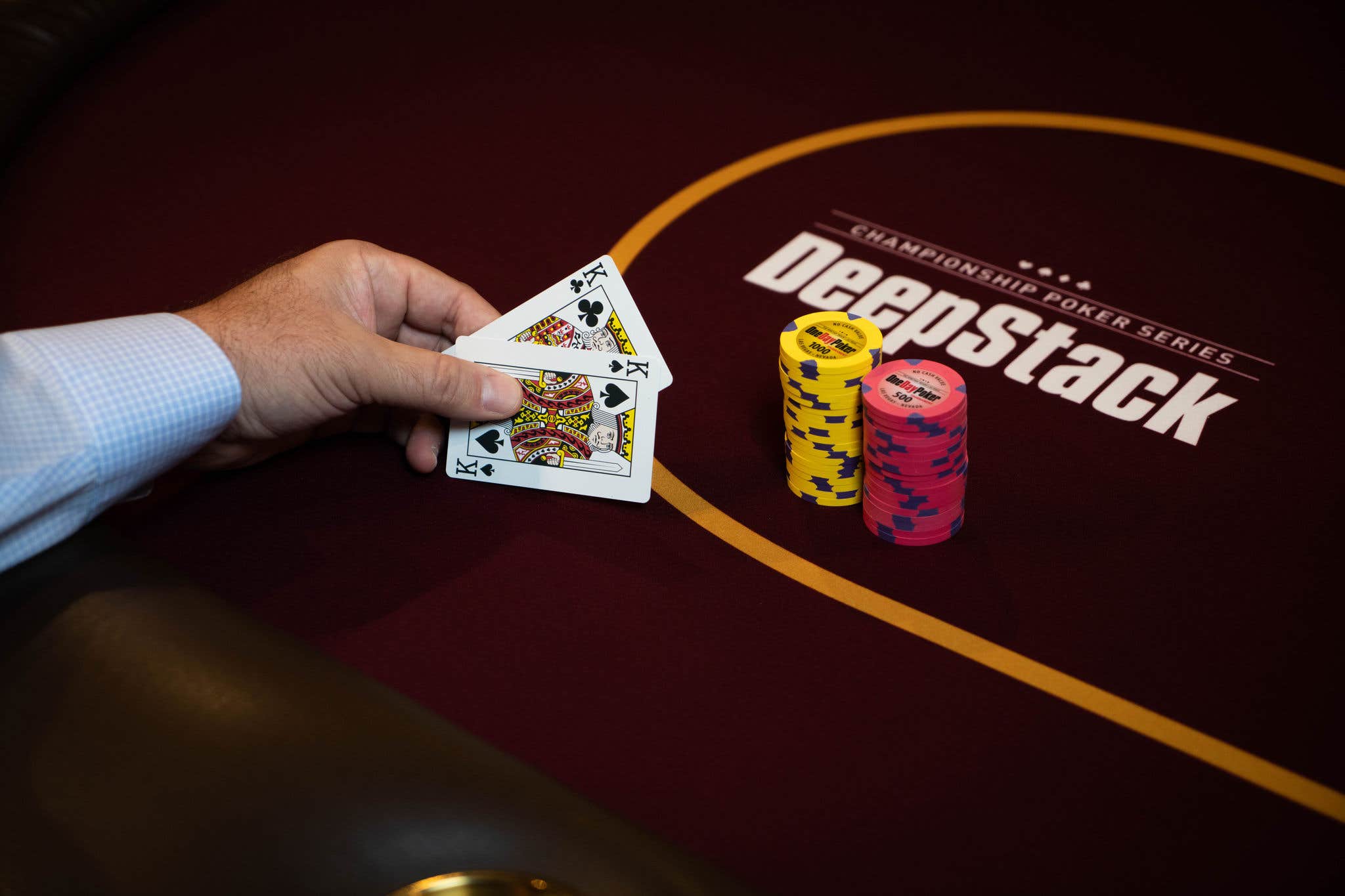 man holding 2 kinds and a stack of poker chips 