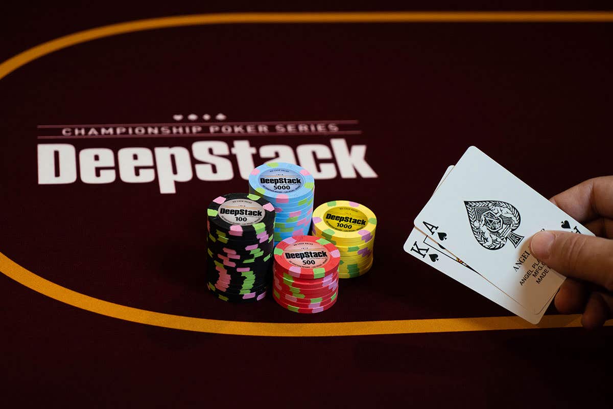 Poker table with stacks of colorful chips and a hand holding Ace and King of Spades.