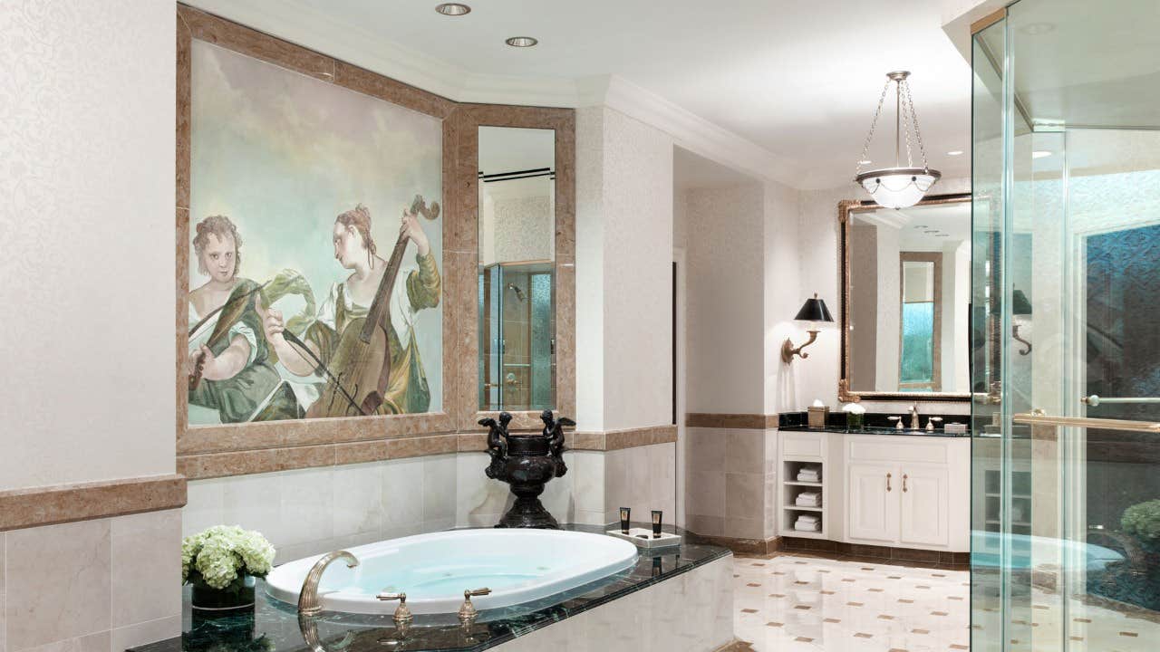 Elegant bathroom with a bathtub, large mirrors, a wall painting of musicians, flower vase, and a glass-enclosed shower.