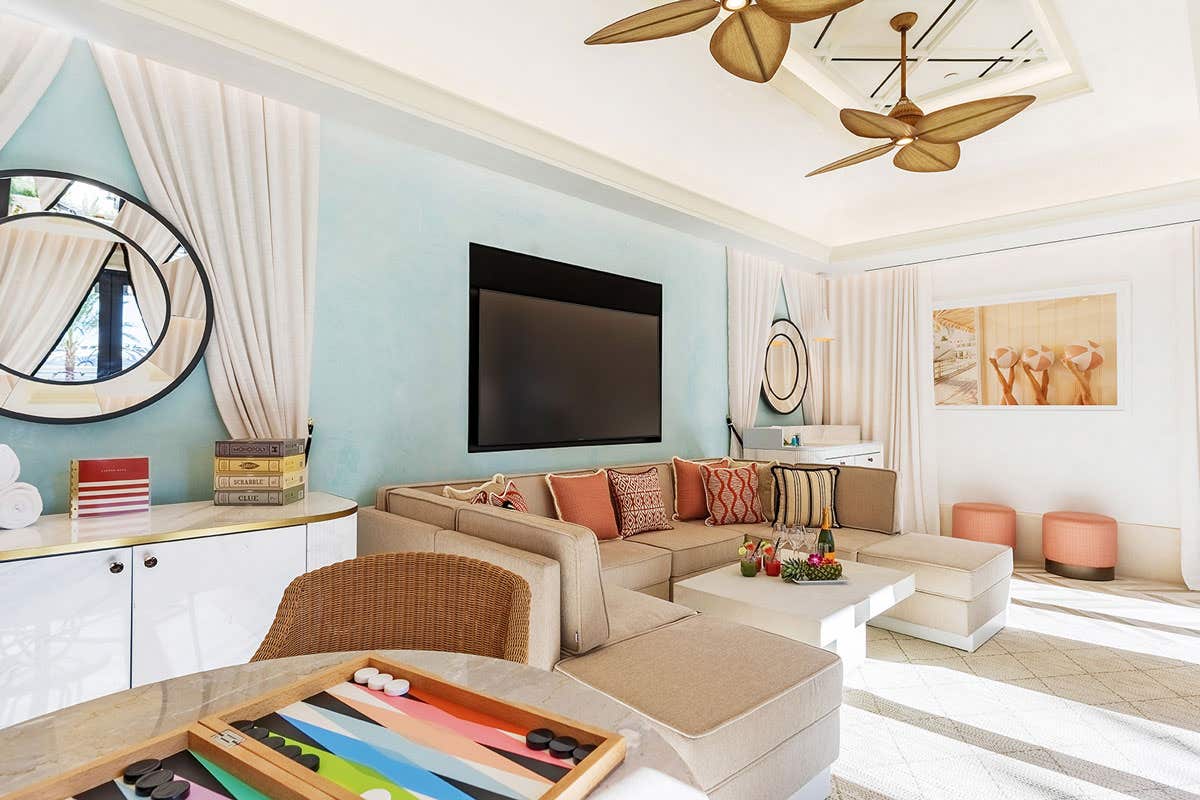 Bright living room with a sectional sofa, wall-mounted TV, and a backgammon board on the table.