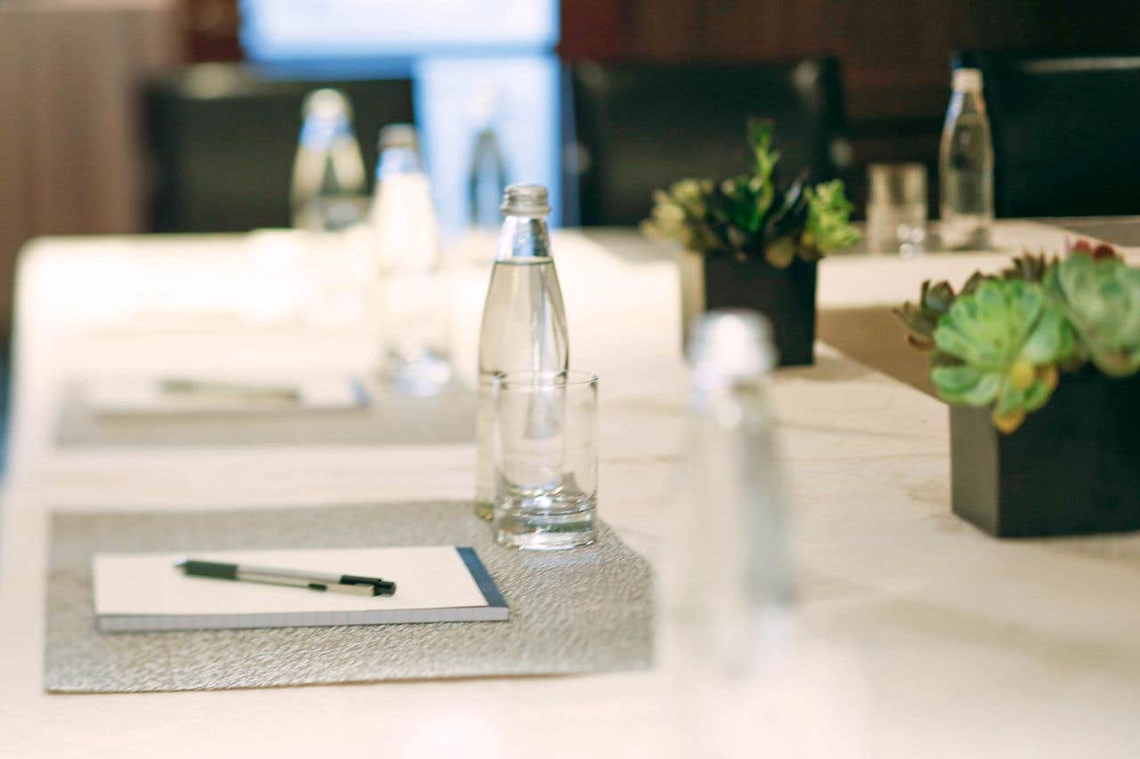 a close up image of a water bottle and a glass on a table with a pad of paper and pen