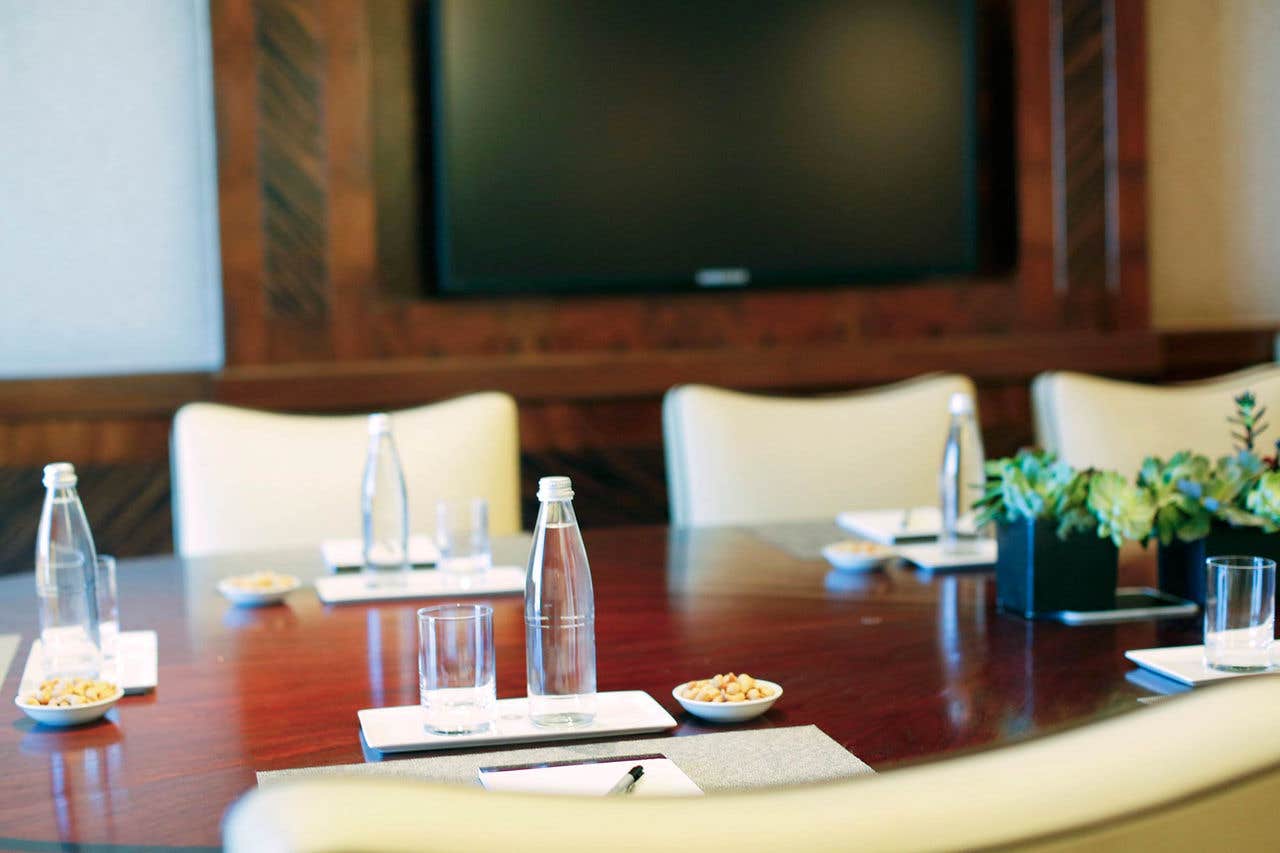 A table with bottles of water, snacks, and a pad of paper and pen. 