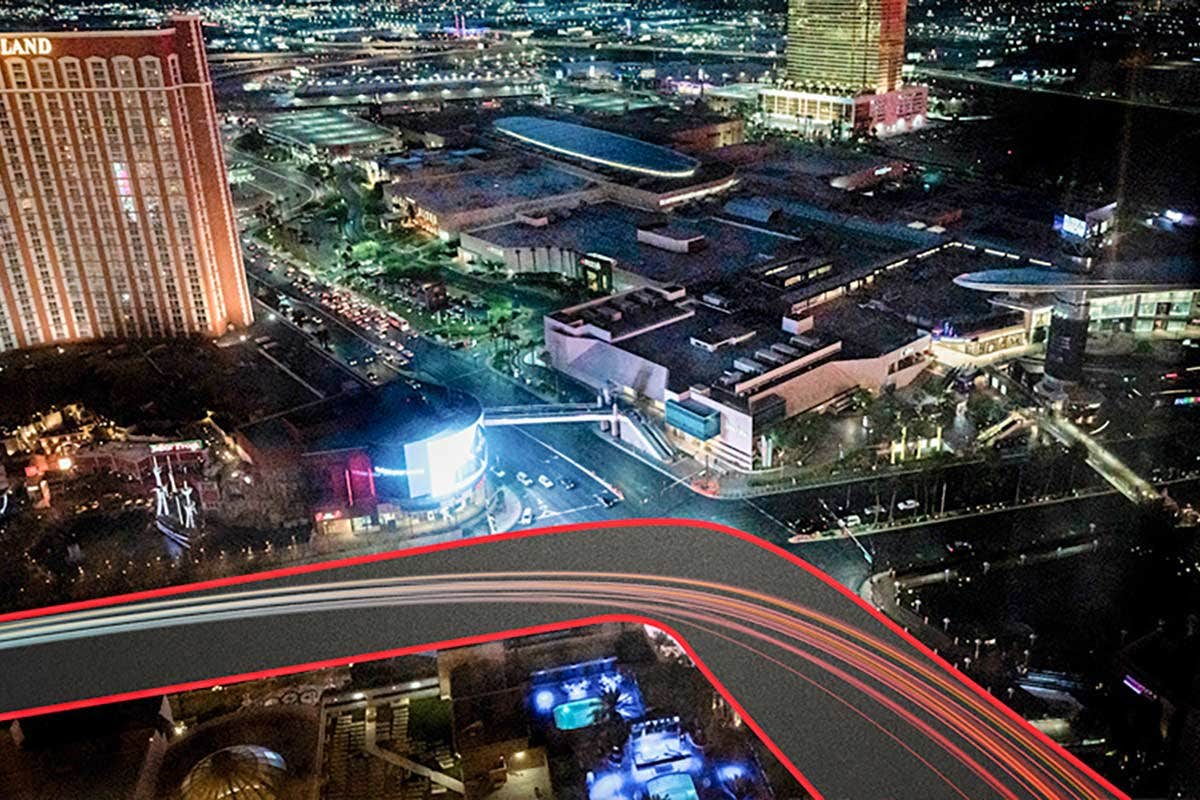 Aerial view of a city at night with illuminated buildings, highways, and light trails from vehicles.