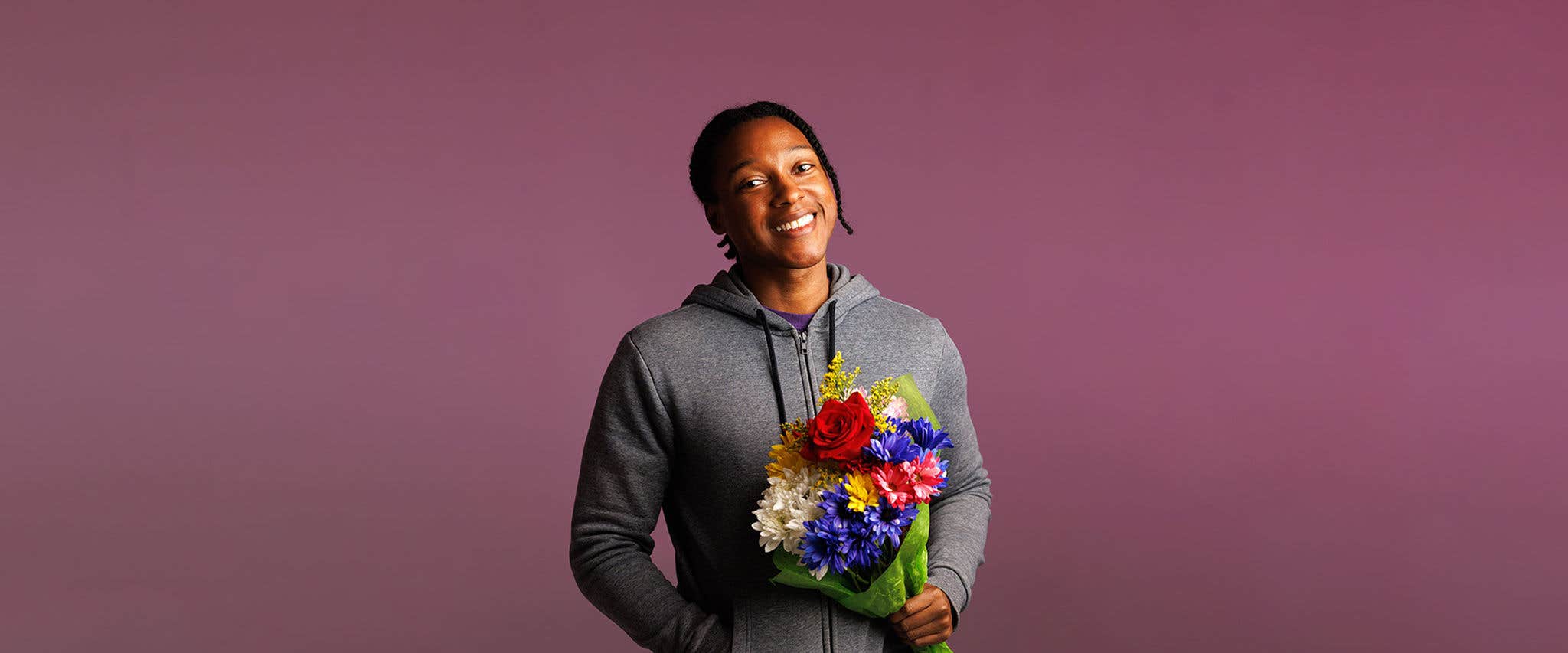 Josh Johnson holding a bouquet in a pink background.