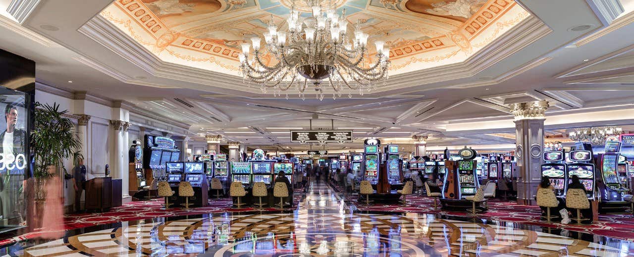 Casino floor with a lot of slot machines, beautiful marble floors and a gorgeous chandelier