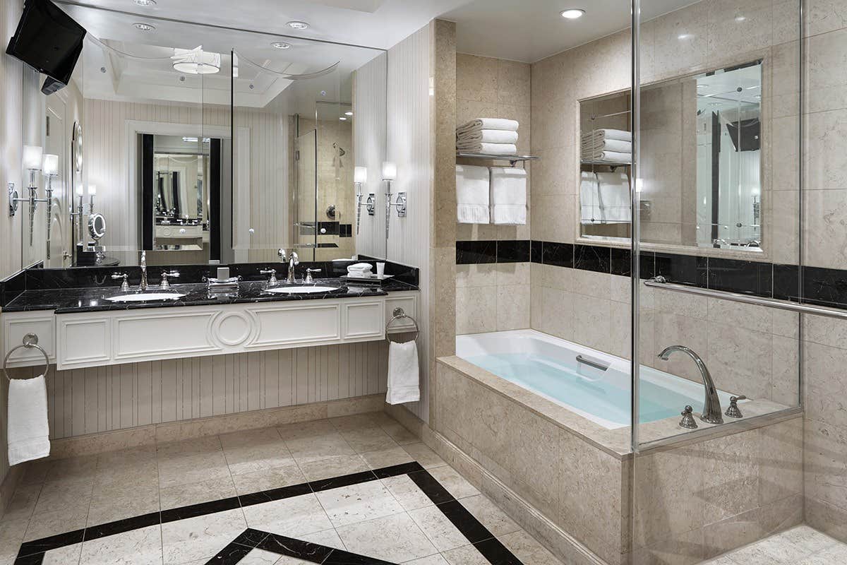 Modern bathroom with a double sink vanity, large mirror, bathtub, tiled floor, and glass-enclosed shower.