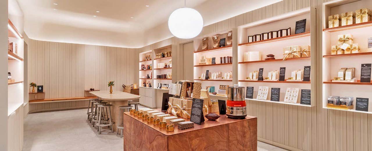 A modern, well-lit store with shelves displaying neatly arranged products and a central table with various items.