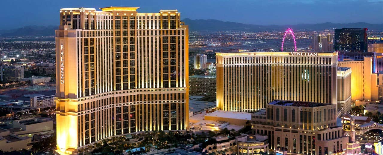 The Las Vegas Strip at dusk with illuminated hotels and the High Roller observation wheel in the background.