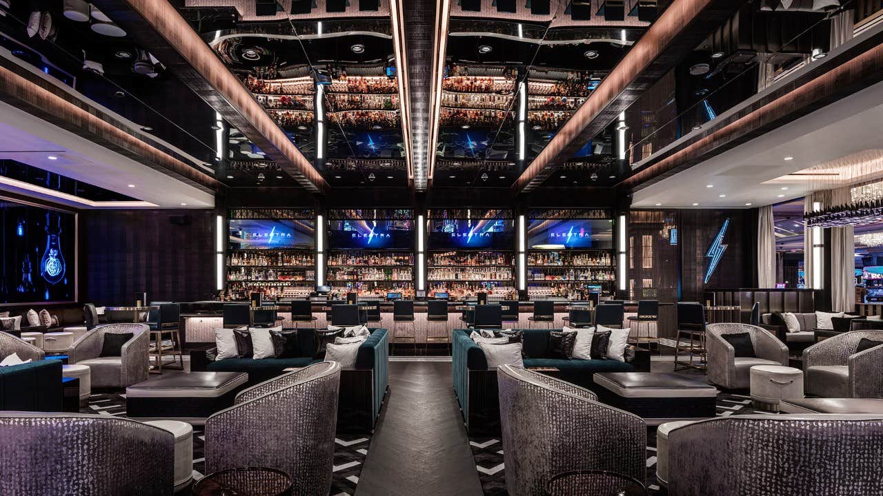 Luxurious modern bar with mirrored ceiling, plush seating, and bottles displayed behind the counter.