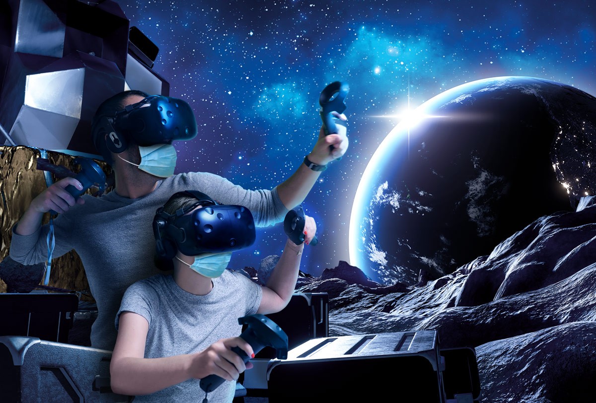 Two people wearing VR headsets and masks, immersed in a space-themed virtual environment.