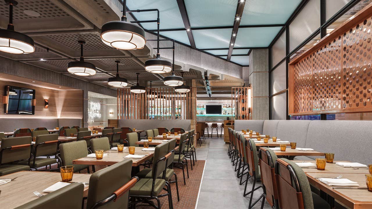 Modern restaurant interior with spacious seating, contemporary lighting, and a minimalist design featuring wooden accents.