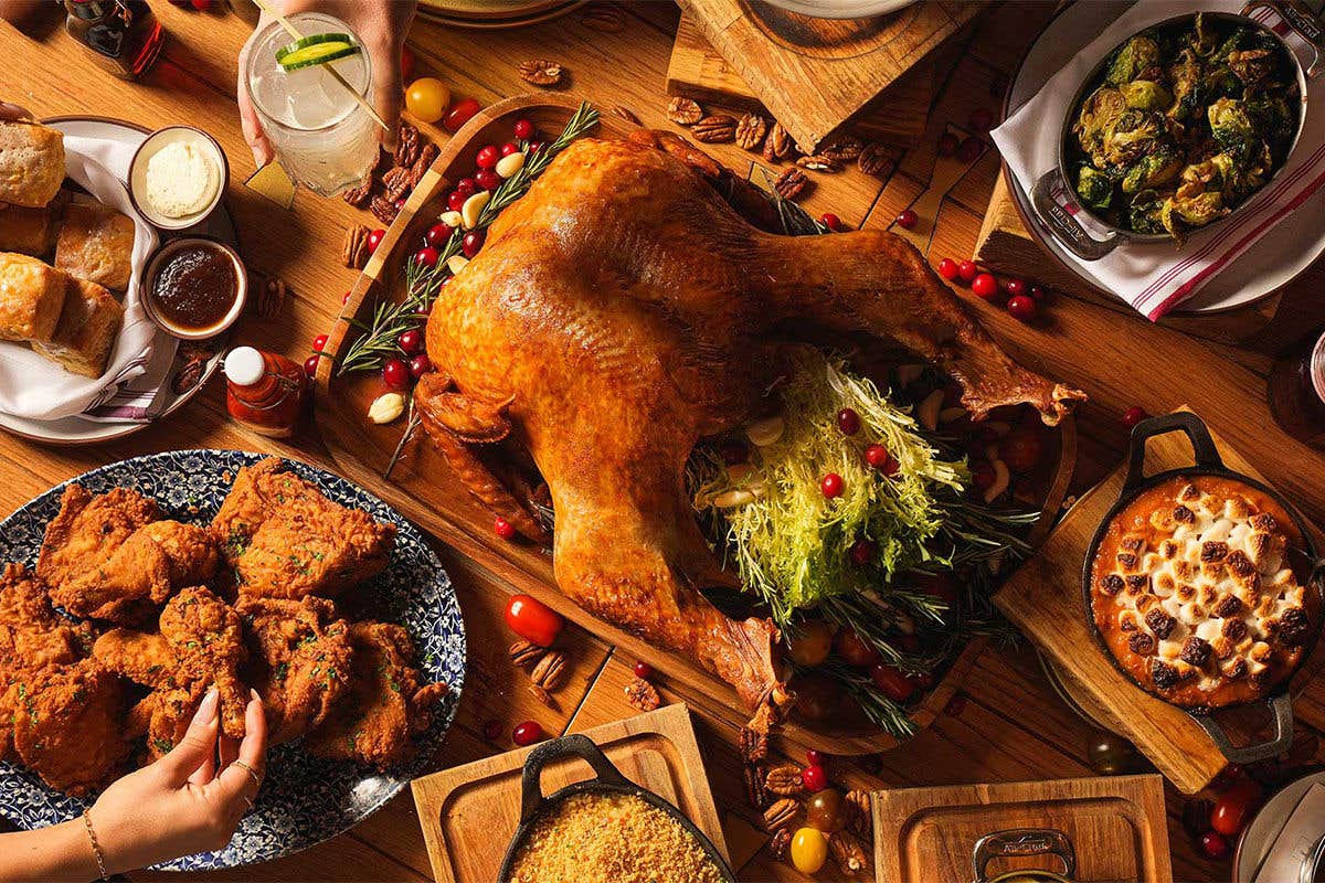 A Thanksgiving feast featuring a roasted turkey, vegetables, breads, and various side dishes on a table.