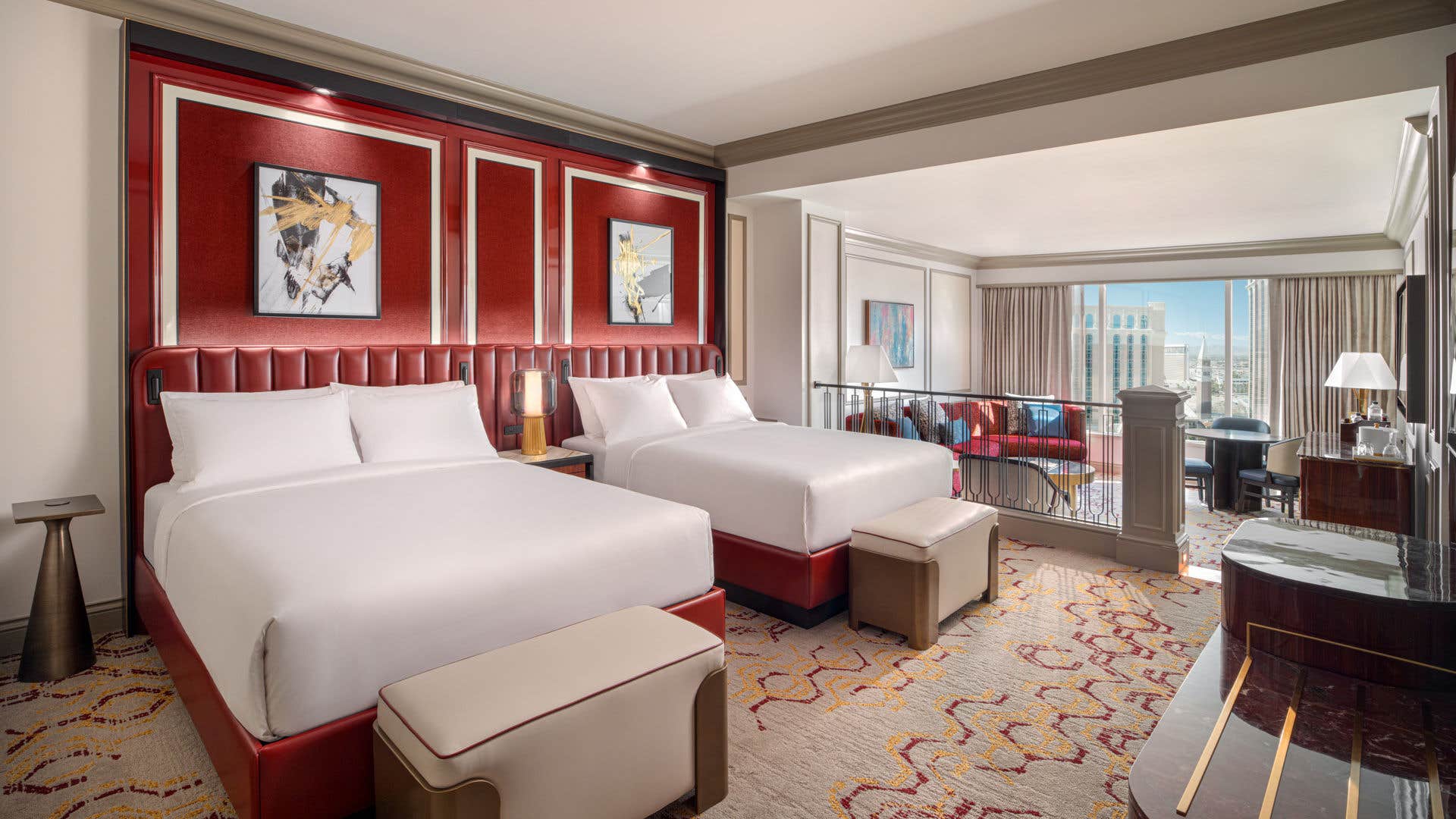 Luxurious hotel room with two double beds, red accents, abstract artwork, and a city view.