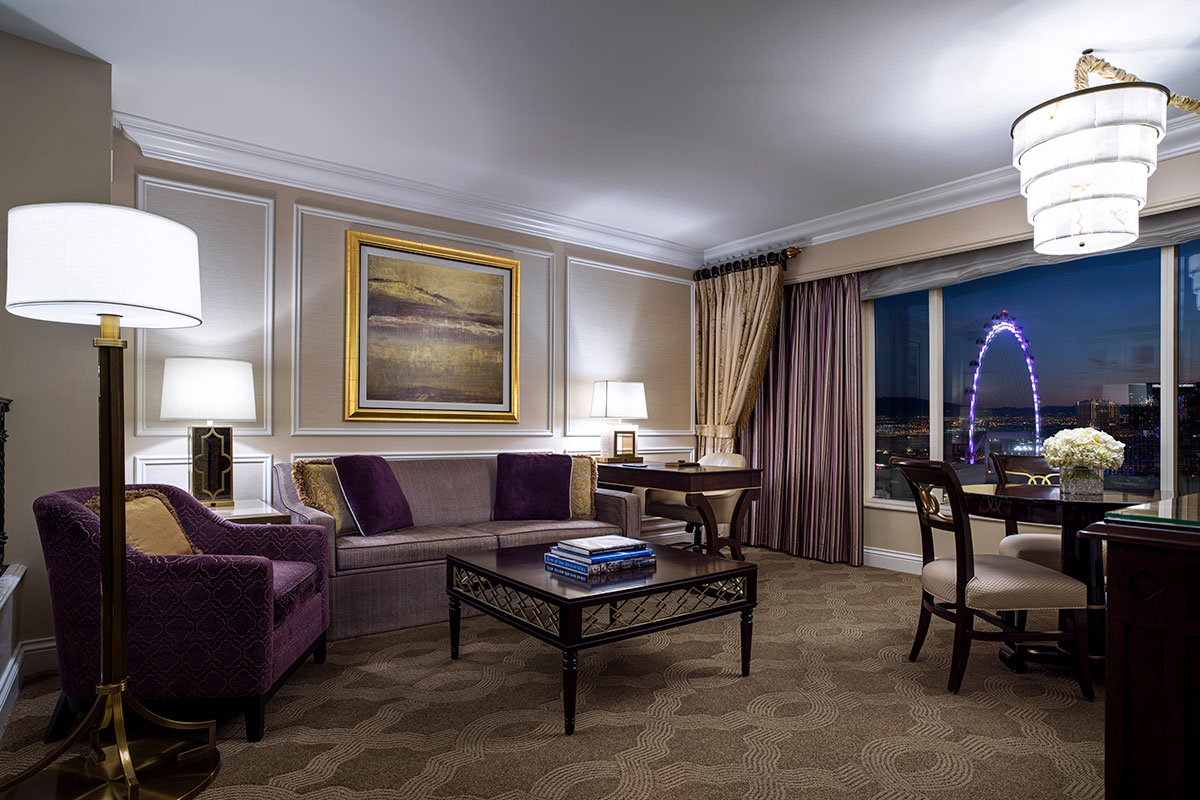 Elegant hotel room with luxurious furnishings, a large window, and a view of a Ferris wheel at night.