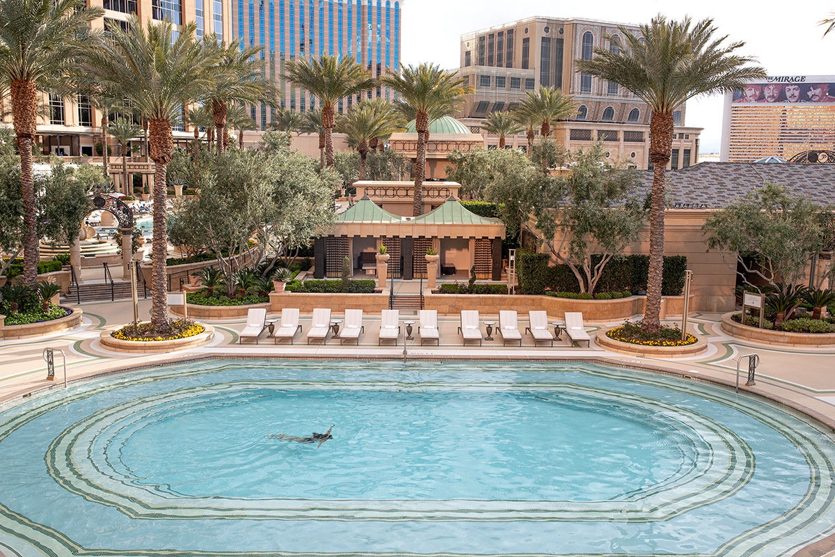 A row of daybeds in front of private poolside cabanas