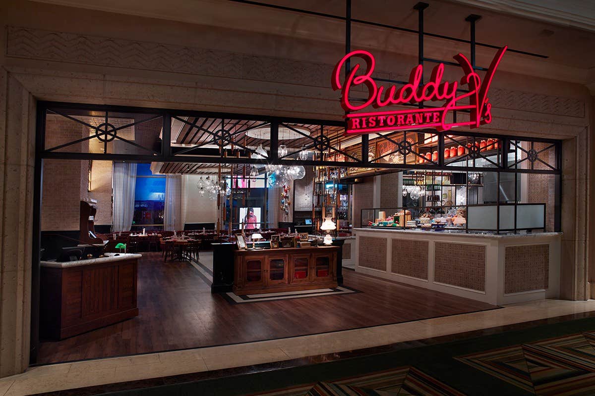 Exterior of Buddy V's Ristorante with neon sign, featuring a modern dining area and wooden accents inside.