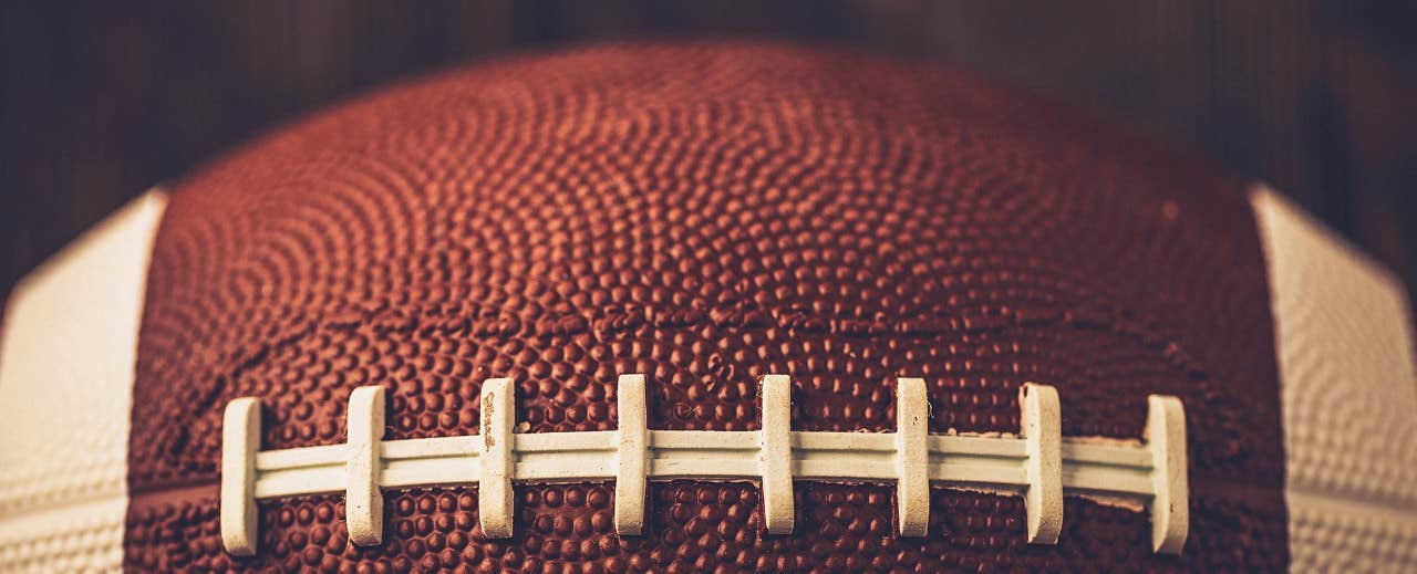 Close-up of the textured surface and white laces of an American football.