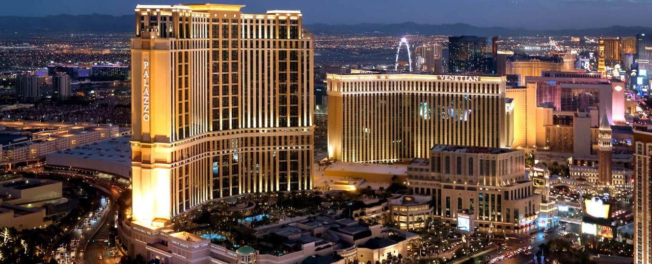 A nighttime aerial view of illuminated hotels and casinos on the Las Vegas Strip, with city lights in the background.